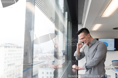 Image of young business man speaking on  smart phone at office