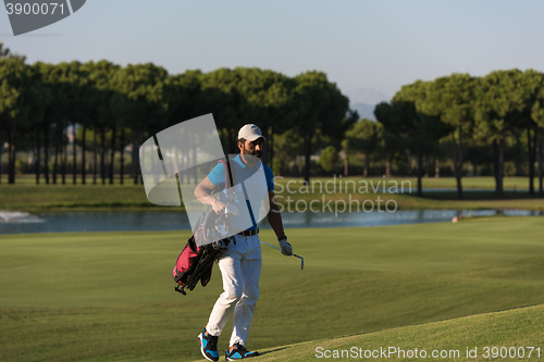 Image of golfer  walking and carrying bag