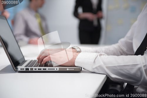 Image of hands typing on laptop at meeting