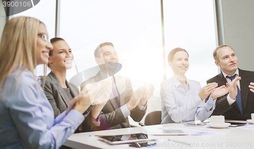 Image of business team with laptop clapping hands