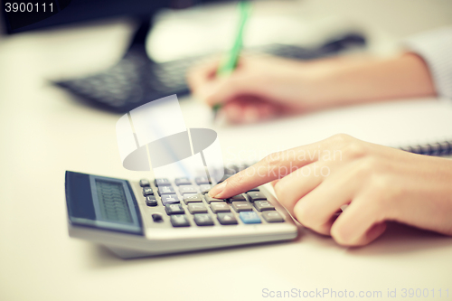 Image of close up of woman with calculator taking notes