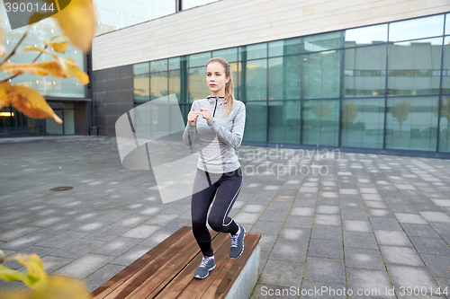 Image of woman making step exercise on city street bench