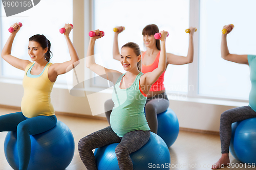 Image of happy pregnant women exercising on fitball in gym