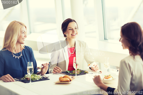 Image of happy women eating and talking at restaurant