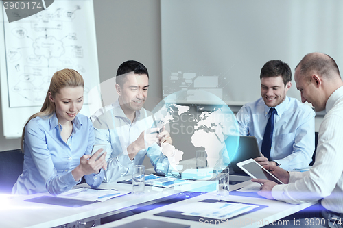 Image of smiling business people with gadgets in office