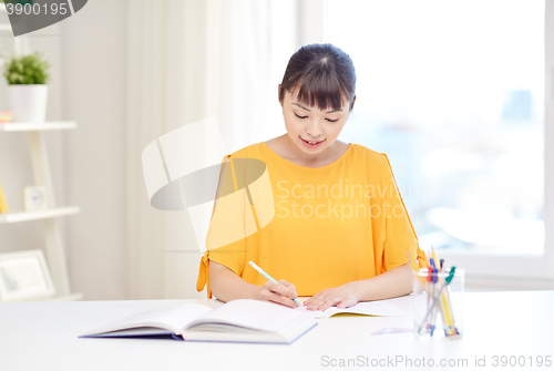 Image of happy asian young woman student learning at home