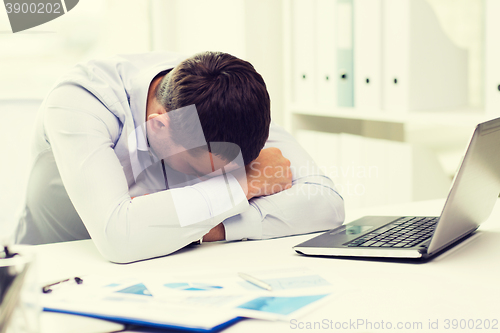 Image of businessman with laptop and papers in office