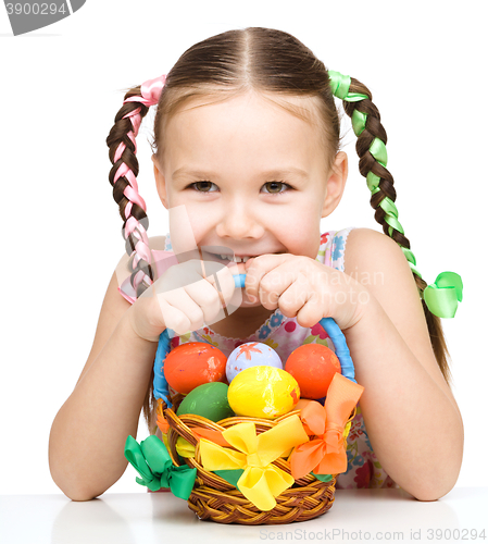 Image of Little girl with basket full of colorful eggs