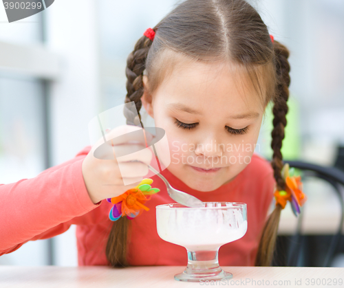 Image of Little girl is eating ice-cream in parlor