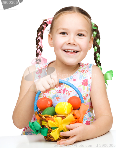 Image of Little girl with basket full of colorful eggs