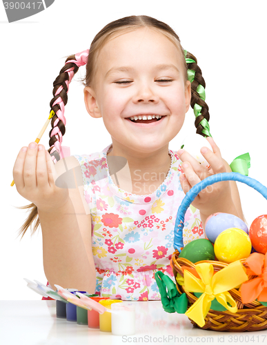 Image of Little girl is painting eggs preparing for Easter