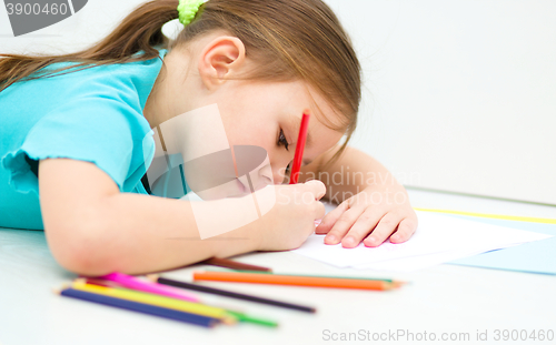 Image of Little girl is drawing using pencils