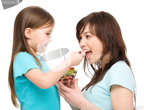 Image of Daughter is feeding her mother with fruit salad