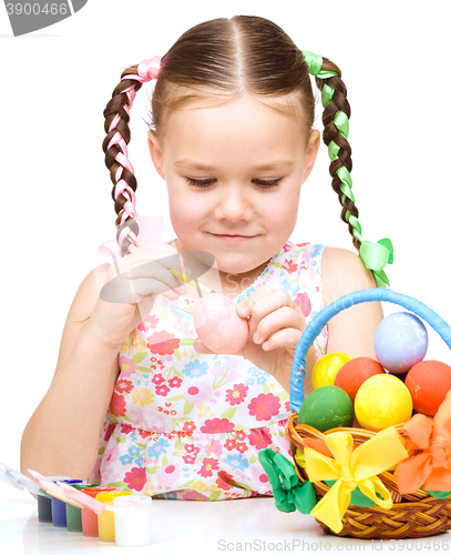 Image of Little girl is painting eggs preparing for Easter