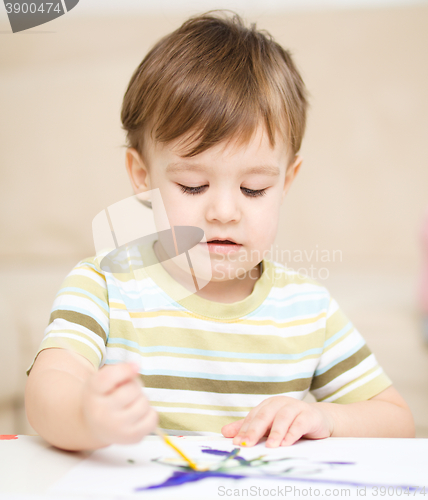 Image of Little boy is playing with paints
