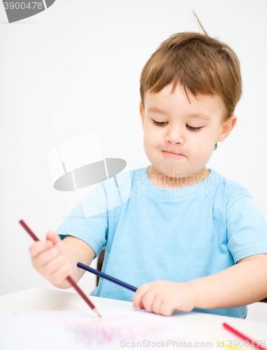 Image of Little boy is drawing on white paper