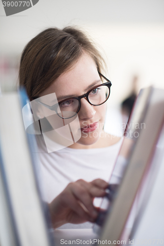 Image of portrait of famale student selecting book to read in library