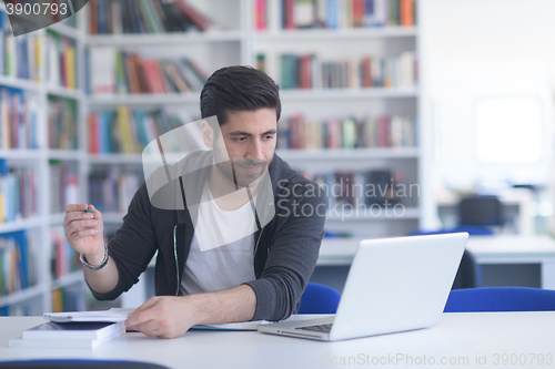 Image of student in school library using laptop for research