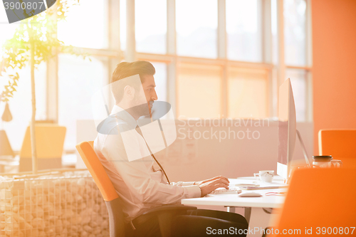 Image of relaxed young businessman first at workplace at early morning