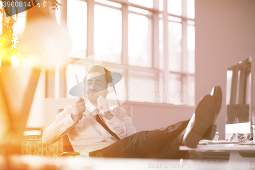 Image of relaxed young businessman first at workplace at early morning