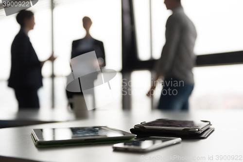 Image of close up of tablet, business people on meeting in background