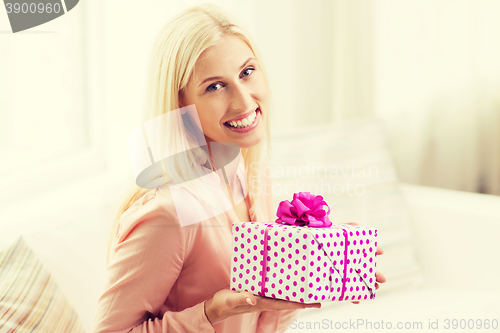 Image of smiling woman with gift box at home