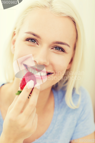 Image of happy woman eating strawberry at home