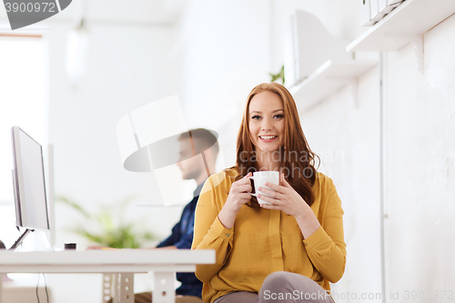 Image of happy woman drinking coffee or tea at office