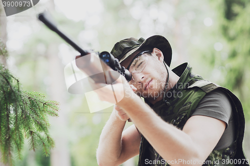 Image of young soldier or hunter with gun in forest