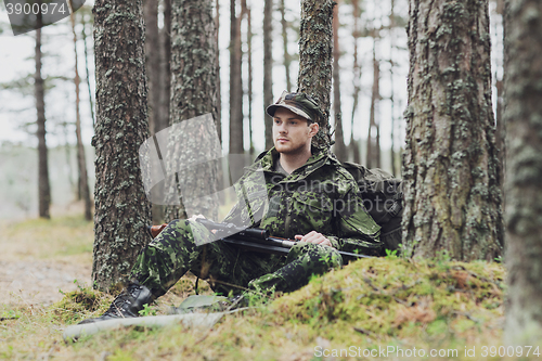 Image of young soldier or hunter with gun in forest