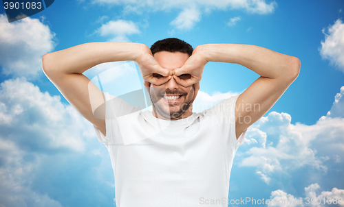 Image of man making finger glasses over sky background