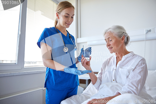 Image of nurse giving medicine to senior woman at hospital