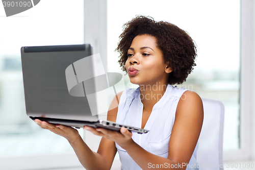 Image of african woman sending kiss to laptop computer