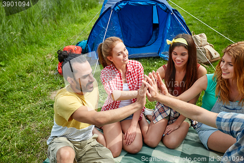 Image of happy friends making high five at camping