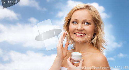 Image of happy woman applying cream to her face