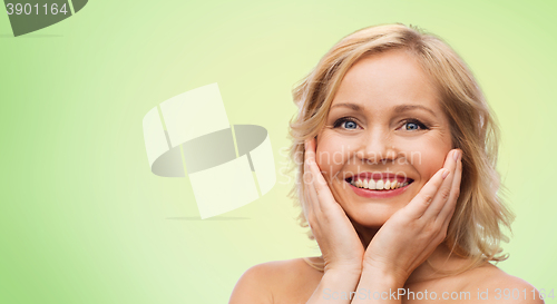 Image of smiling woman with bare shoulders touching face