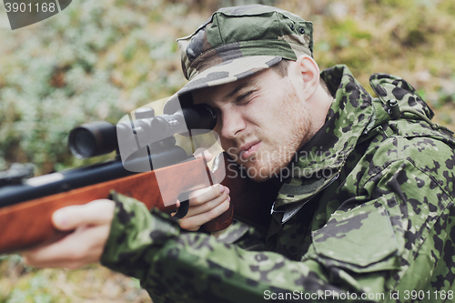 Image of young soldier or hunter with gun in forest