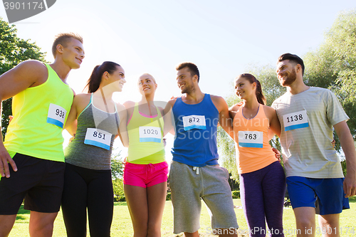 Image of happy friends or couple with racing badge numbers