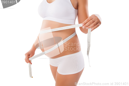 Image of Pregnant woman measuring her stomach with tape