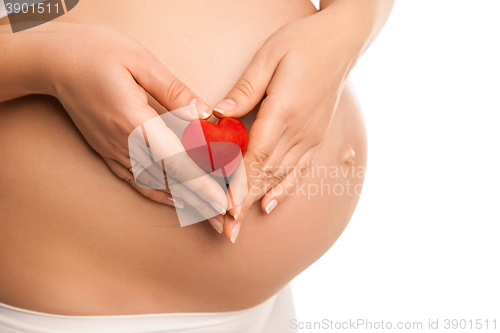 Image of pregnant woman holding  heart symbol over white