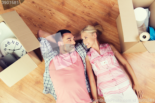 Image of happy couple lying on floor among cardboard boxes