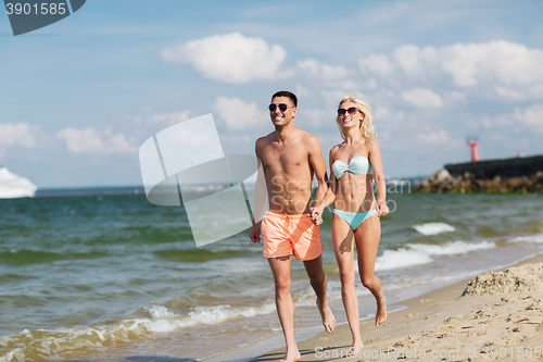 Image of happy couple in swimwear running on summer beach