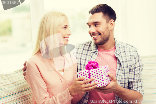 Image of happy man giving woman gift box at home