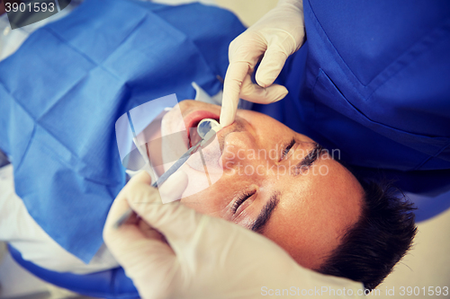 Image of close up of dentist checking male patient teeth