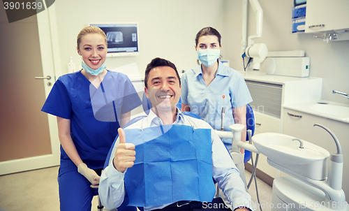 Image of happy female dentists with man patient at clinic