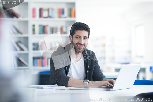 Image of student in school library using laptop for research