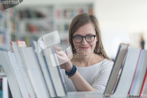 Image of portrait of famale student selecting book to read in library