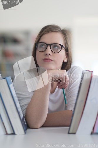 Image of portrait of famale student selecting book to read in library