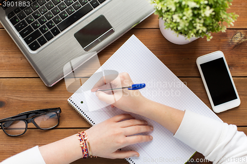 Image of close up of woman or student writing to notepad