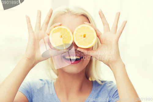 Image of happy woman having fun covering eyes with lemon